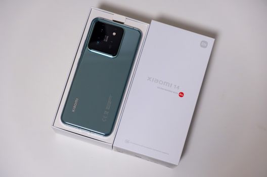 Mint green smartphone in brand new packaging on a white surface.