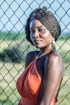 在哥伦比亚乔科，一位身着橙色连衣裙的优雅女子在铁丝网围栏旁摆姿势