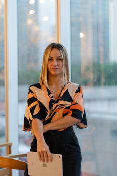 Portrait of a confident businesswoman standing indoors with a tablet, showcasing professionalism.