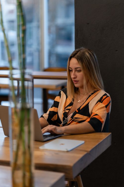Free Young woman focused on laptop work inside a trendy café with a laptop. Stock Photo
