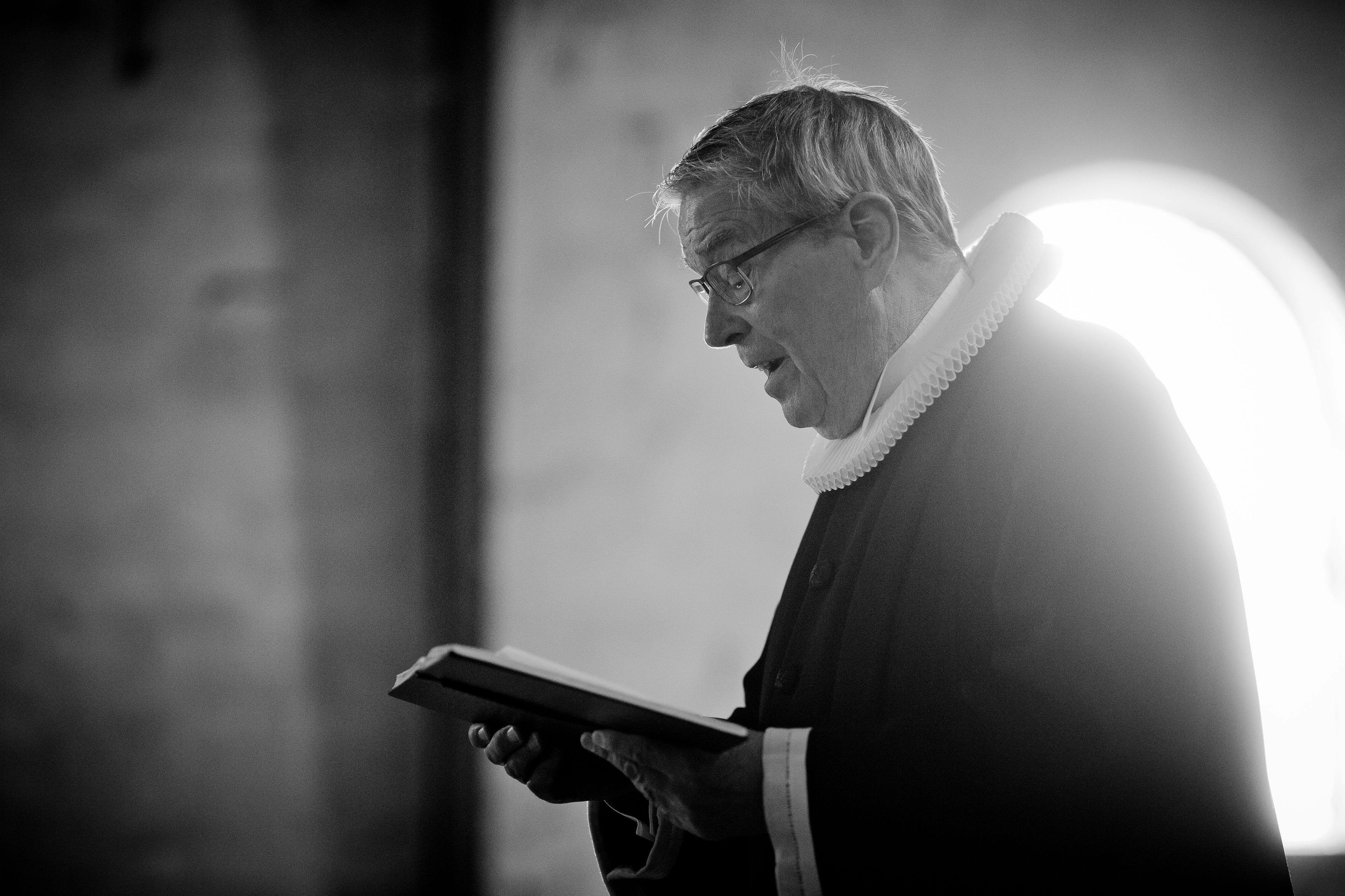 室内，一位年长的男性宗教领袖正在阅读，侧影中透出坦率而沉思的心情