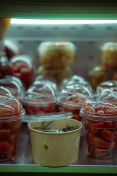 Plastic containers with cherry tomatoes in a supermarket fridge.