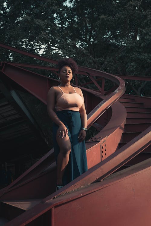 Woman in Pink and Teal Dress Standing on Stairs