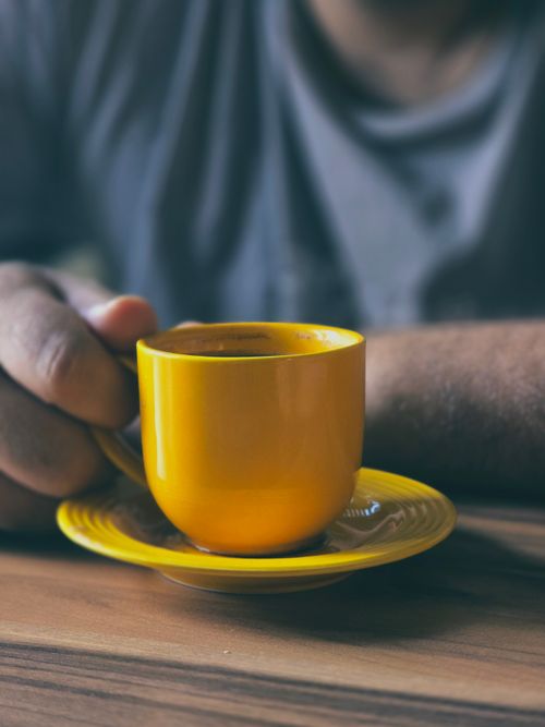 Free Close-up of a person holding a vibrant yellow coffee cup, creating a warm morning vibe. Stock Photo