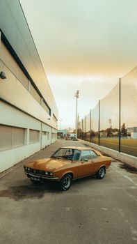 Classic vintage car parked between buildings under a warm sunset.