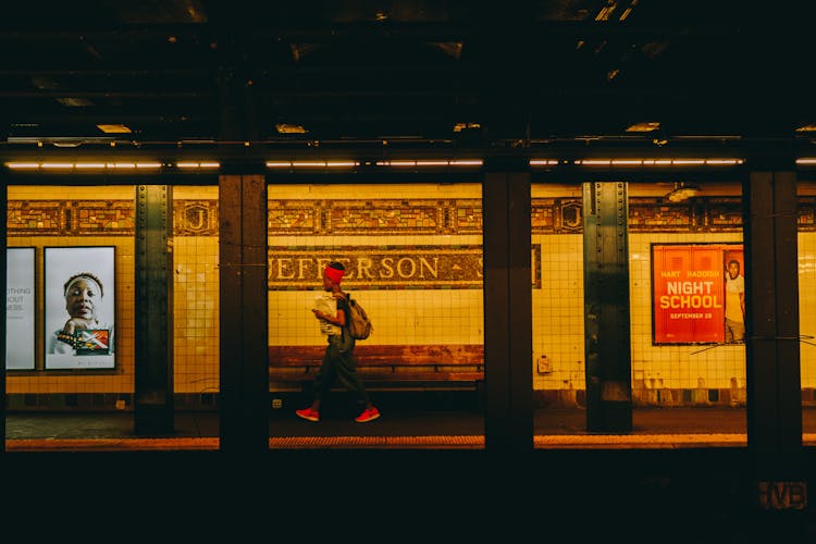 Person Wearing Black Top And Red Bandana Walking On Subway