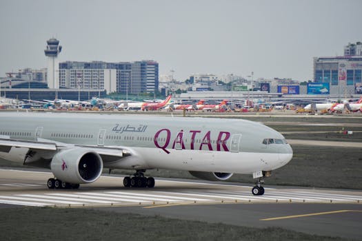 Qatar Airways airplane taxiing on the runway at a busy international airport.
