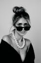 一个戴着墨镜和珍珠项链的女人的黑白肖像，散发着优雅