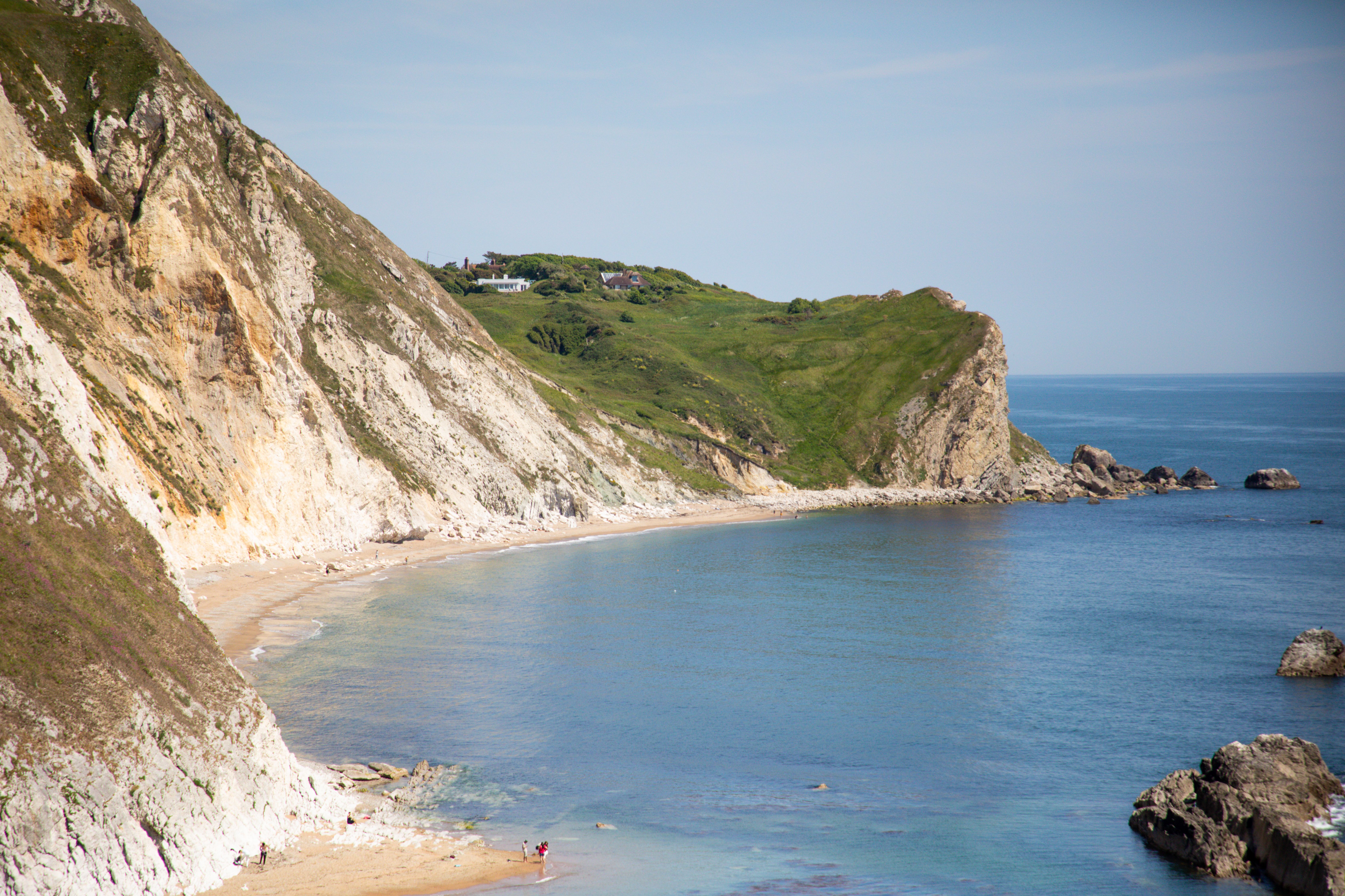 Scenic view of Durdle Door's coastal cliffs and beach in summer, England.