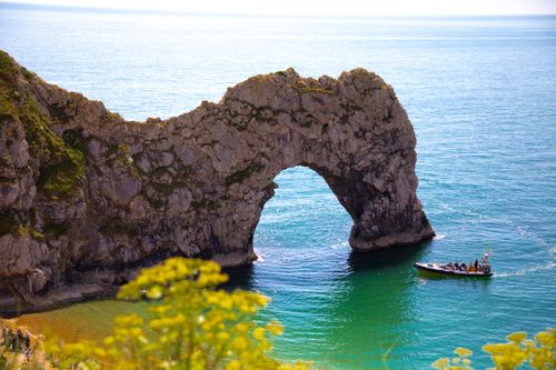 Free Picturesque arch of Durdle Door with a boat on the sparkling sea in Dorset, England. Stock Photo