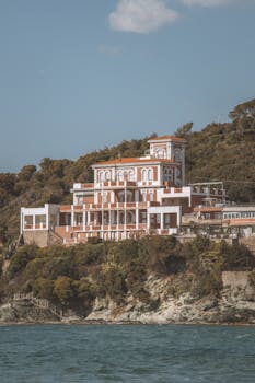 Stunning Mediterranean-style villa perched on a cliff with ocean view, evoking luxury and elegance.