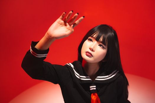Artistic portrait of young woman in a sailor-inspired outfit against a vivid red backdrop, expressing creativity.