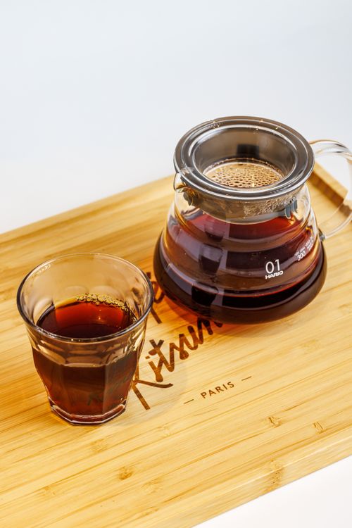 Free A glass and carafe of freshly brewed black coffee placed on a bamboo tray with 'PARIS' inscription. Stock Photo