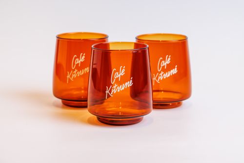 Free Three orange glass tumblers featuring the Café Kitsuné logo with a clean white background. Stock Photo