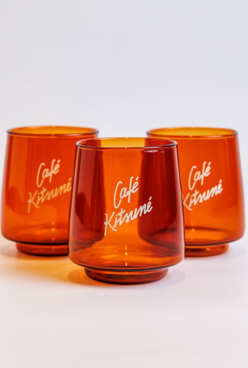 Free Three orange glasses branded with Café Kitsuné, placed on a white background. Stock Photo