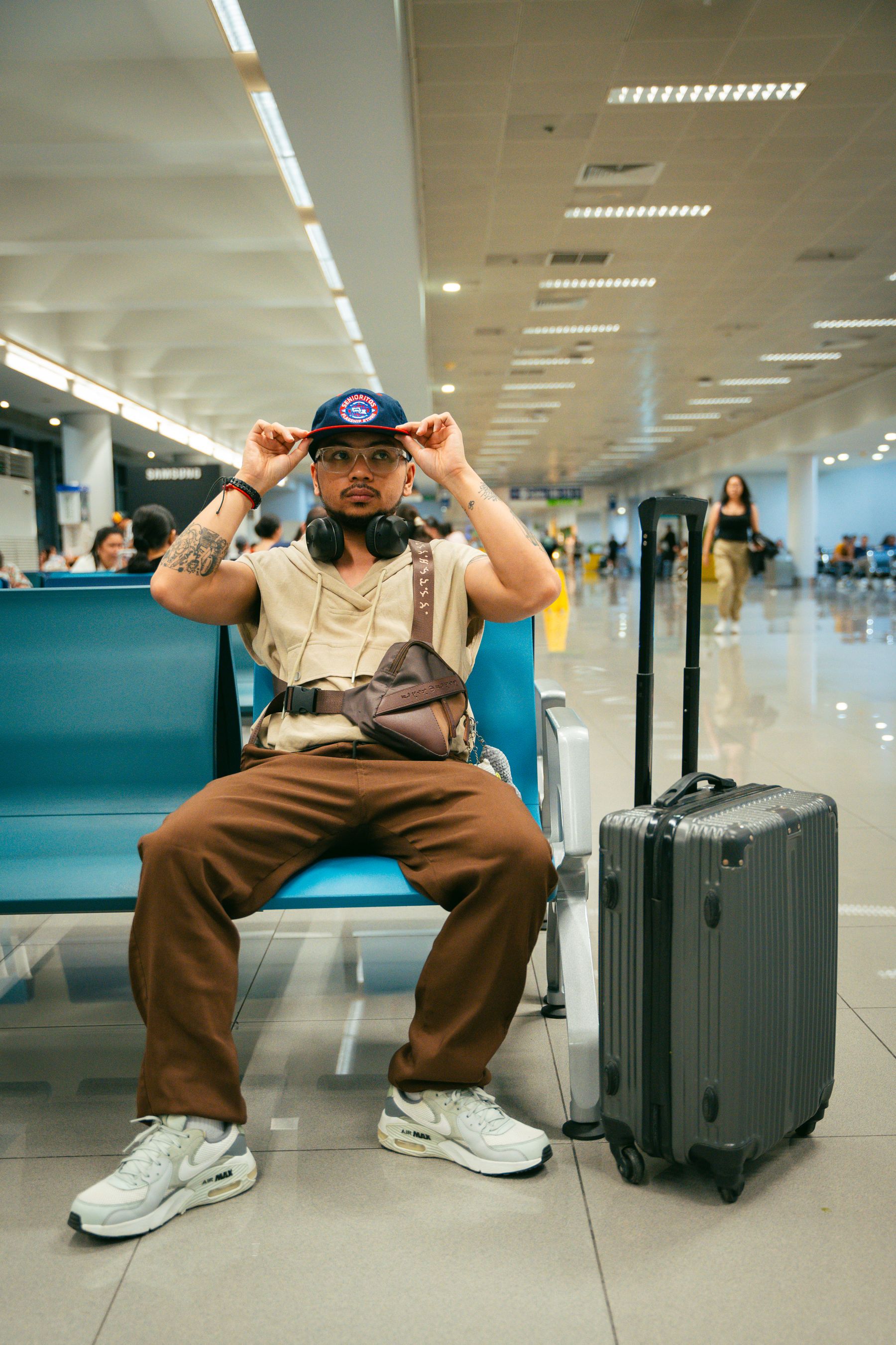 Traveler waiting in a bright airport terminal beside rolling luggage