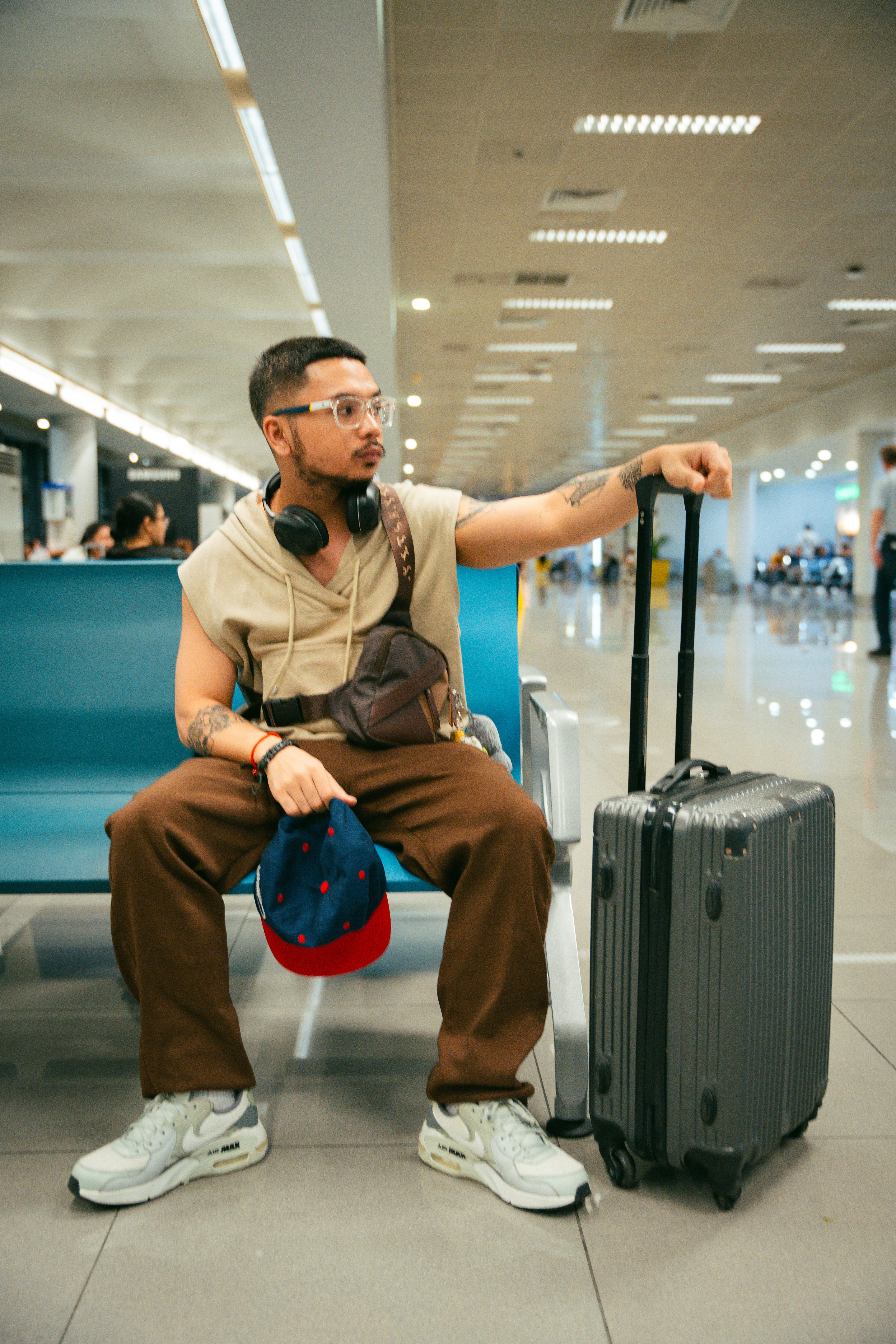 jovem viajando sozinho sentado no saguão do aeroporto com mala de viagem