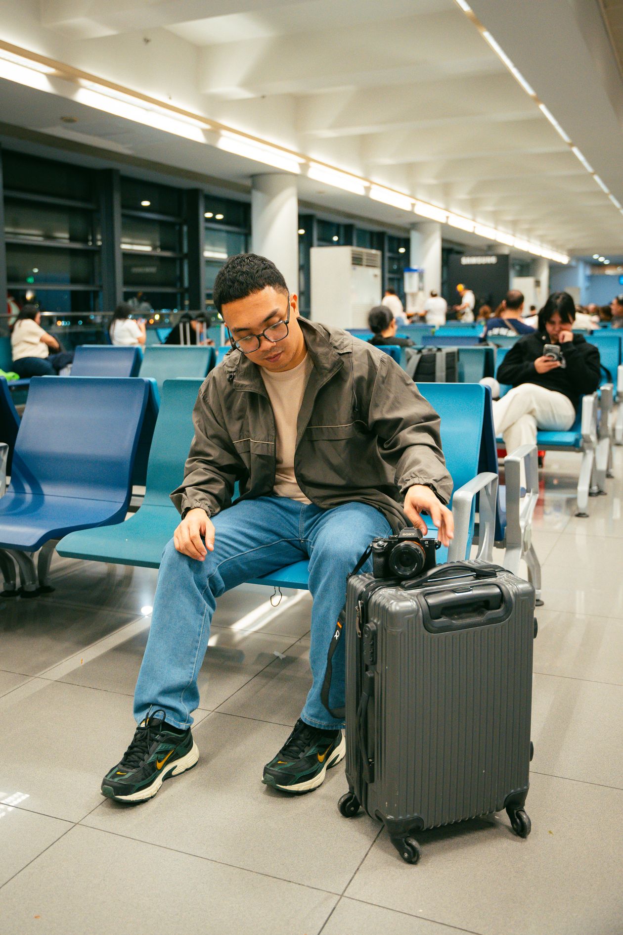 Traveler sitting in a modern airport terminal beside luggage