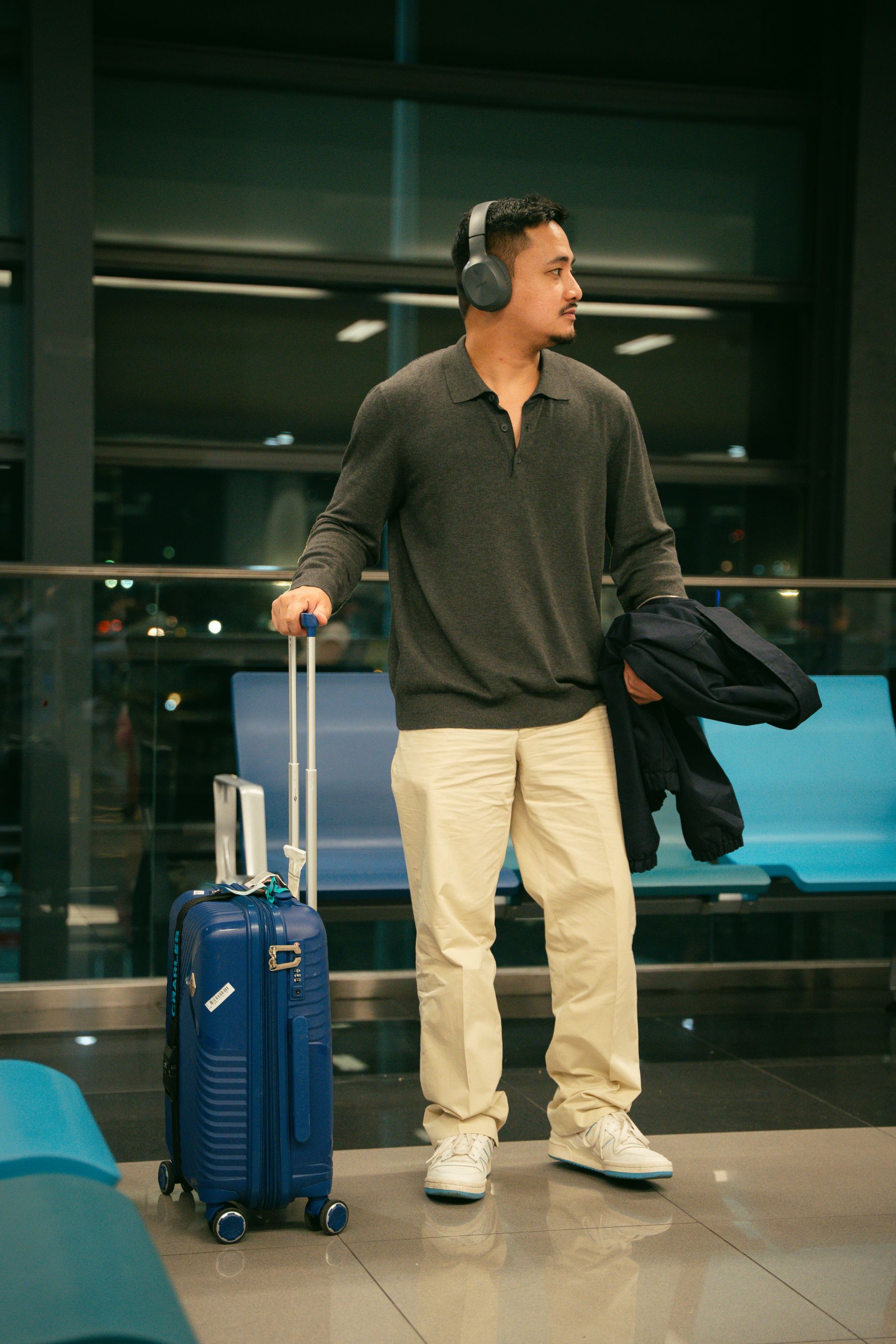 Traveler waiting with a suitcase inside a modern airport terminal