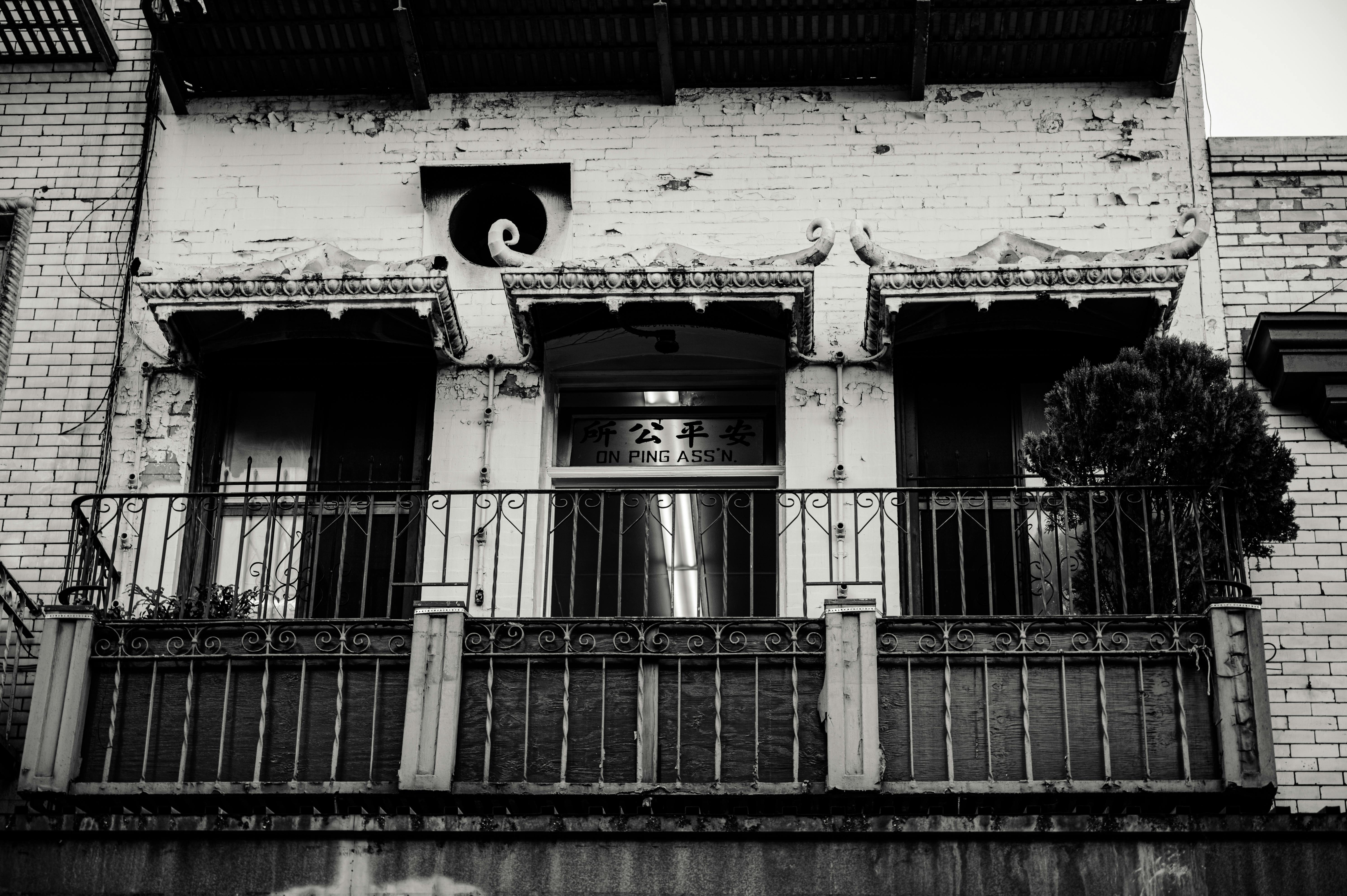 一张黑白照片中的城市建筑，立面复古而斑驳，突显了建筑的阳台