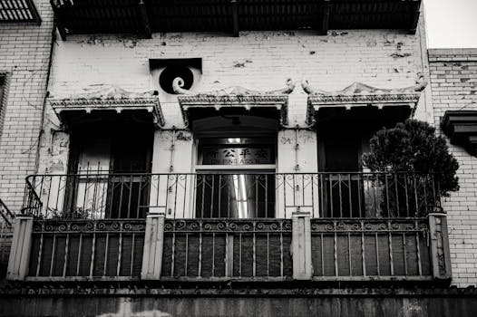 一张黑白照片中的城市建筑，立面复古而斑驳，突显了建筑的阳台