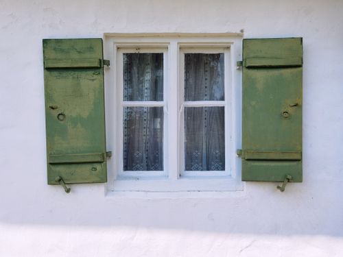 Free Vintage window with green wooden shutters on a white textured wall, capturing rustic charm. Stock Photo