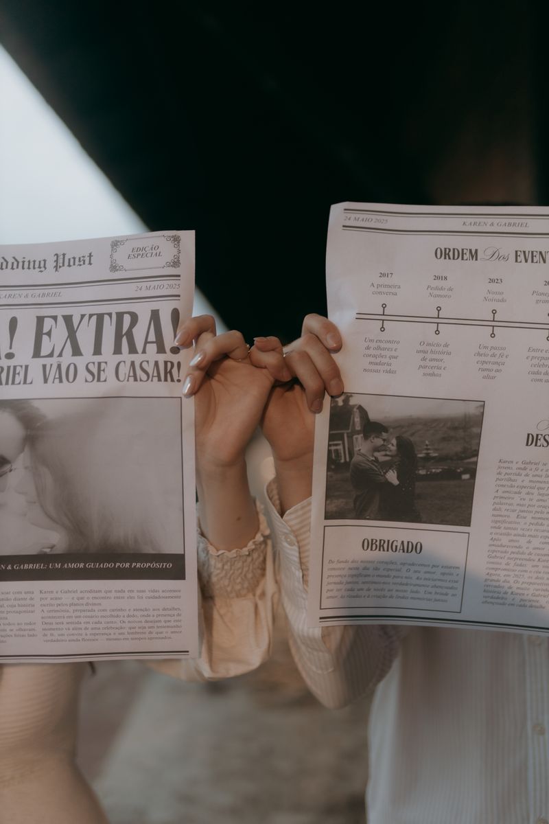 A couple's hands holding newspapers with romantic headlines, creating a vintage mood.