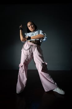 Confident female dancer striking a pose in studio lighting, showcasing energy and style.