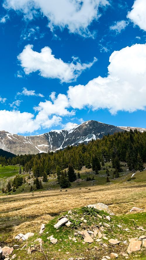 Free Scenic view of mountains under a bright blue sky with fluffy clouds. Stock Photo