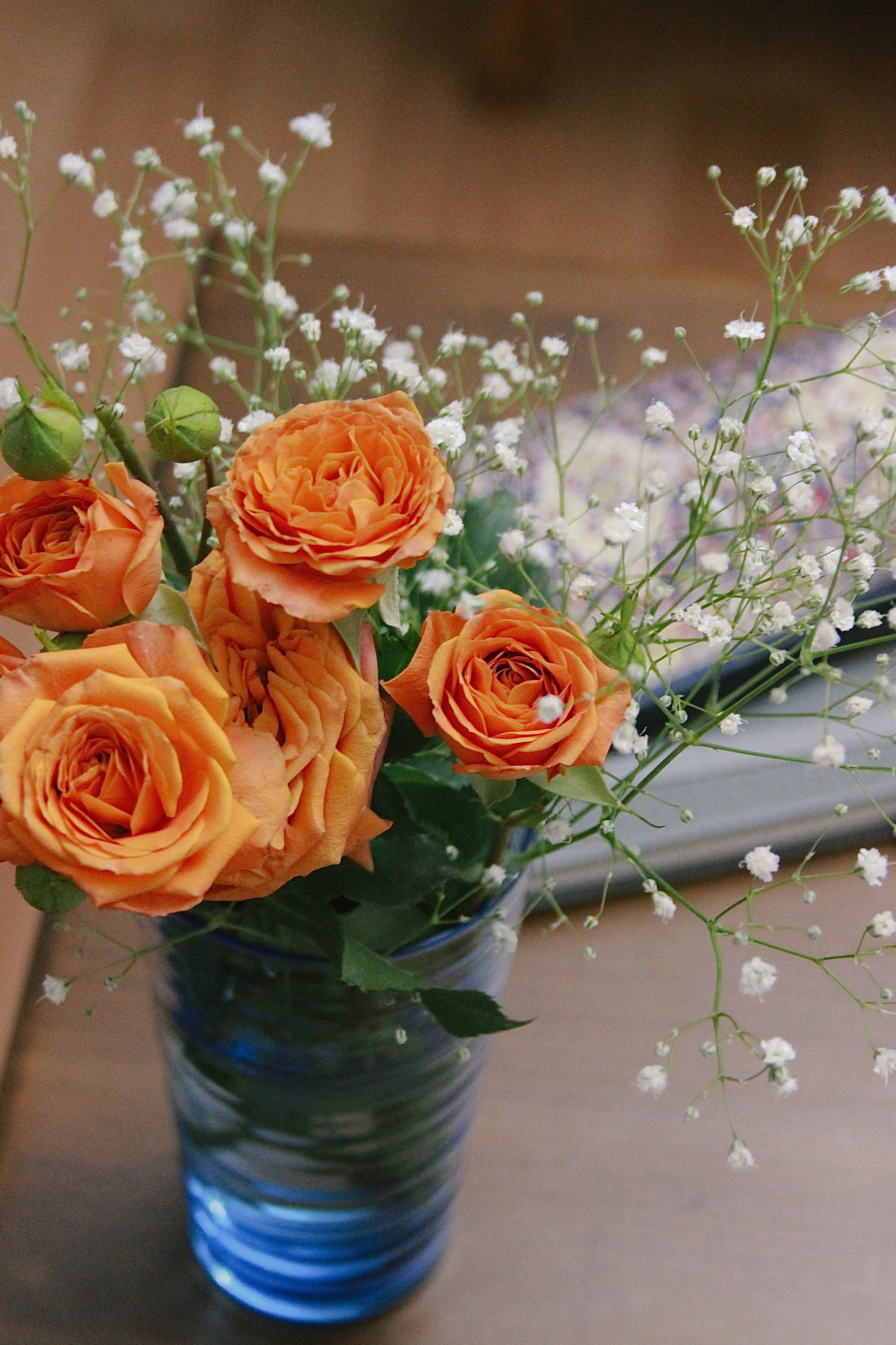 [ColoSach]-a-beautiful-arrangement-of-orange-roses-and-baby's-breath-in-a-blue-glass-vase.