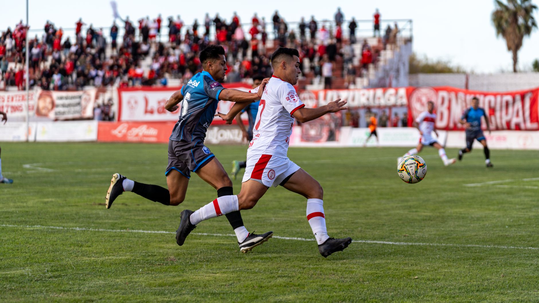 two football wing-backs sprinting down opposite touchlines during a tense evening league match
