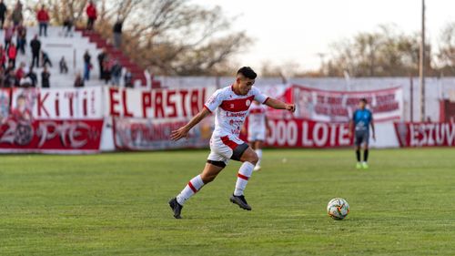 Free A football player in action on the field during an outdoor match with spectators in the background. Stock Photo