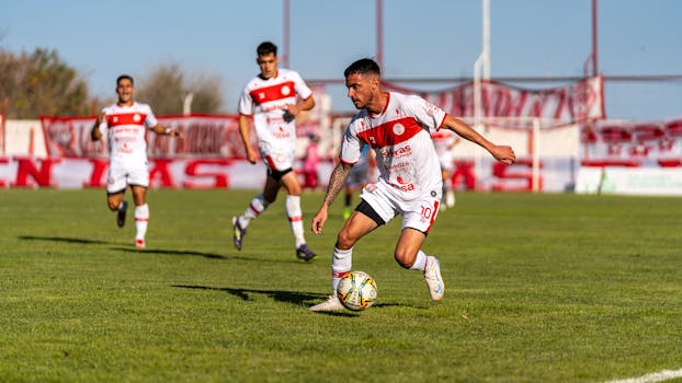 Players engaged in a competitive soccer match outdoors on a sunny day.
