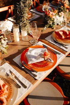 Beautiful outdoor dining setup with elegant tableware and floral decor at sunset.