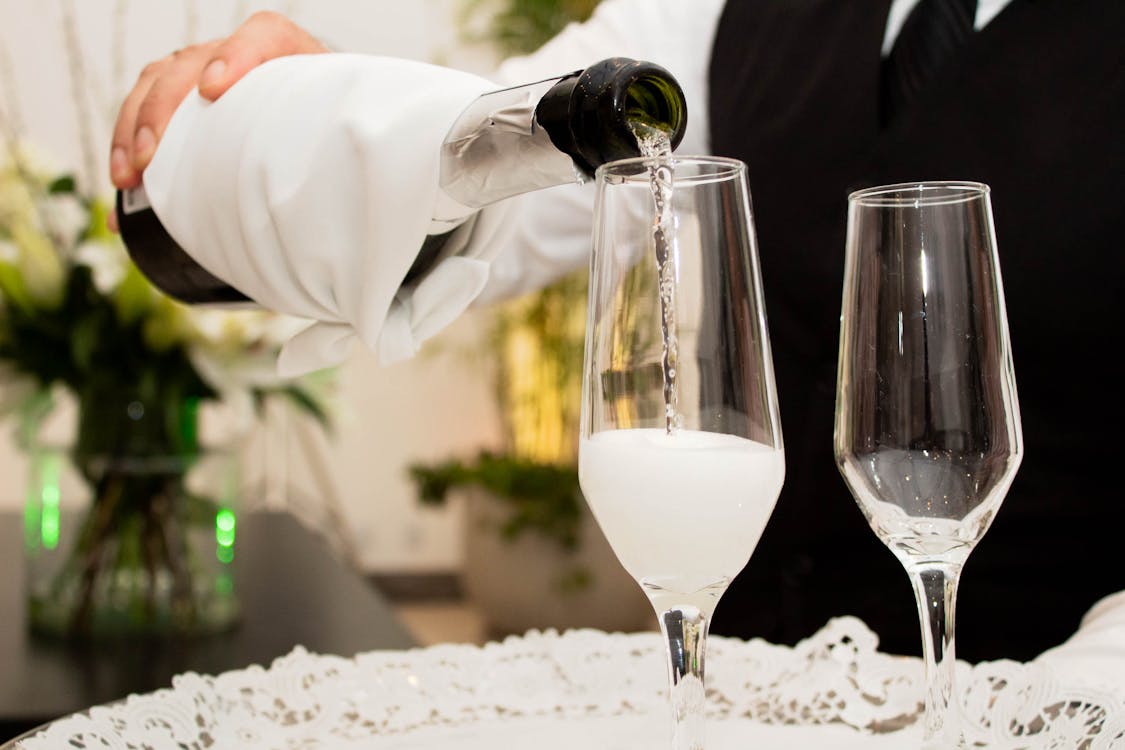 Free Close-up of champagne being poured into glasses at a sophisticated celebration. Stock Photo