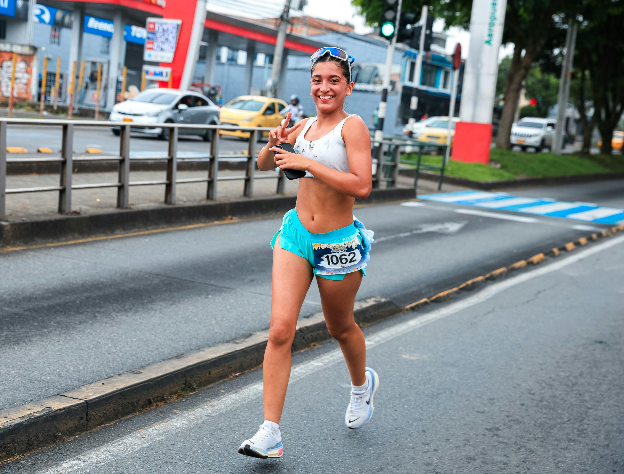 Smiling woman in athletic wear running in a city marathon on a sunny day.