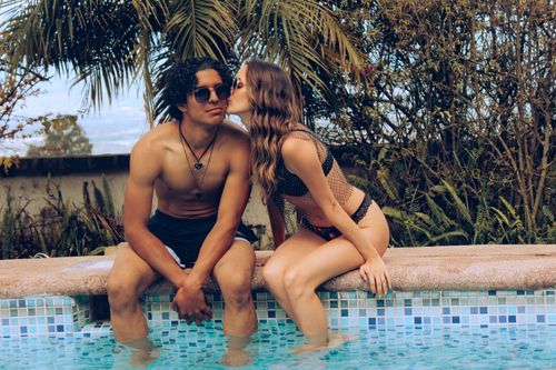Free A young couple enjoys a sunny day by the pool in a tropical paradise, exuding warmth and love. Stock Photo