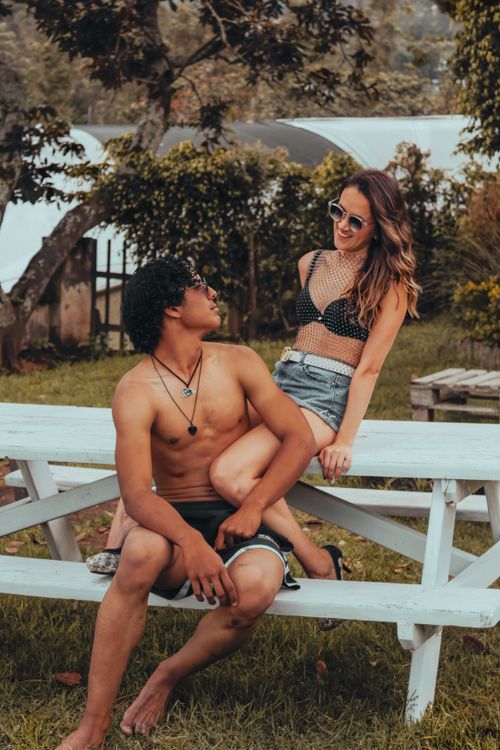 Free A young couple enjoy a sunny day together in a garden setting, sitting on a picnic bench. Stock Photo