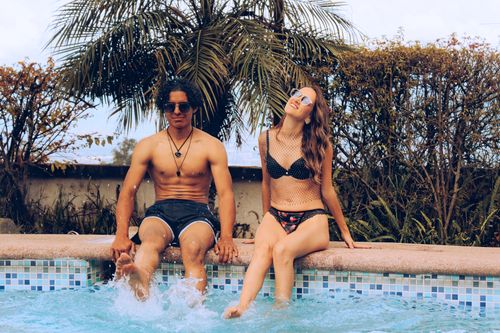 Free A man and woman enjoying a sunny day by the pool, capturing a vibrant and relaxed atmosphere. Stock Photo