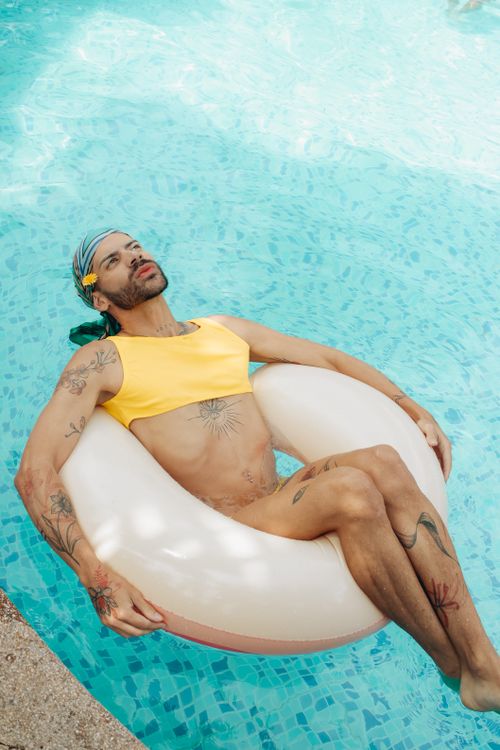 Free Tattooed man floating in a pool on a summer day, showcasing vibrant tattoos and a relaxed posture. Stock Photo