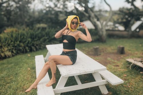 Free A fashionable woman with a yellow scarf enjoys a sunny day at an outdoor picnic area. Stock Photo