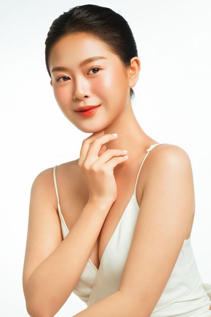 Portrait of an elegant Asian woman with flawless skin in a high-key studio setting, embodying modern beauty.
