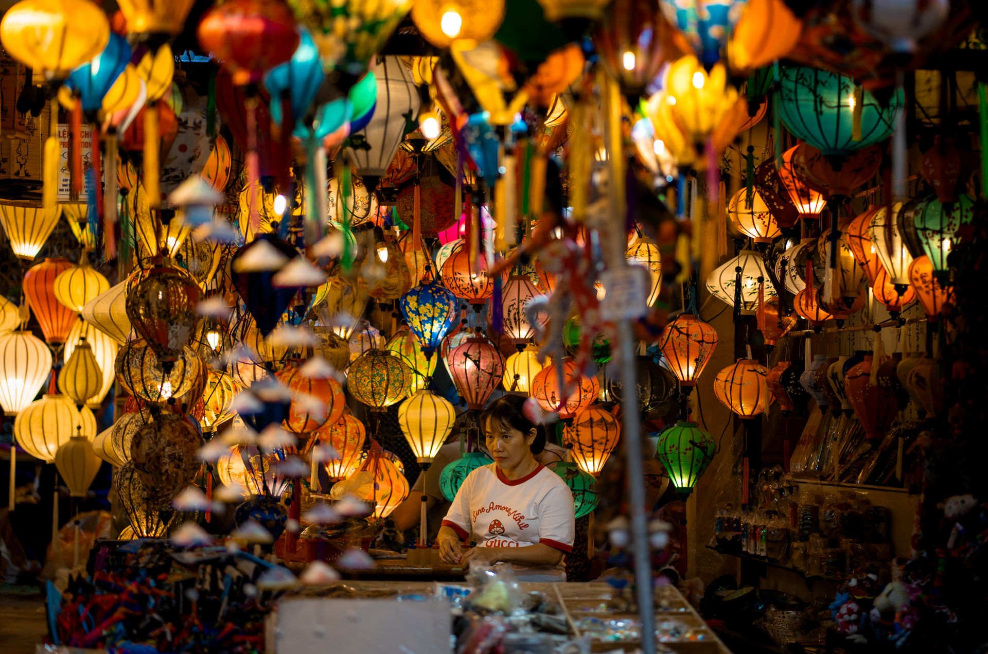 Vibrant lantern shop with diverse hanging lanterns and owner inside, creating a warm ambiance.