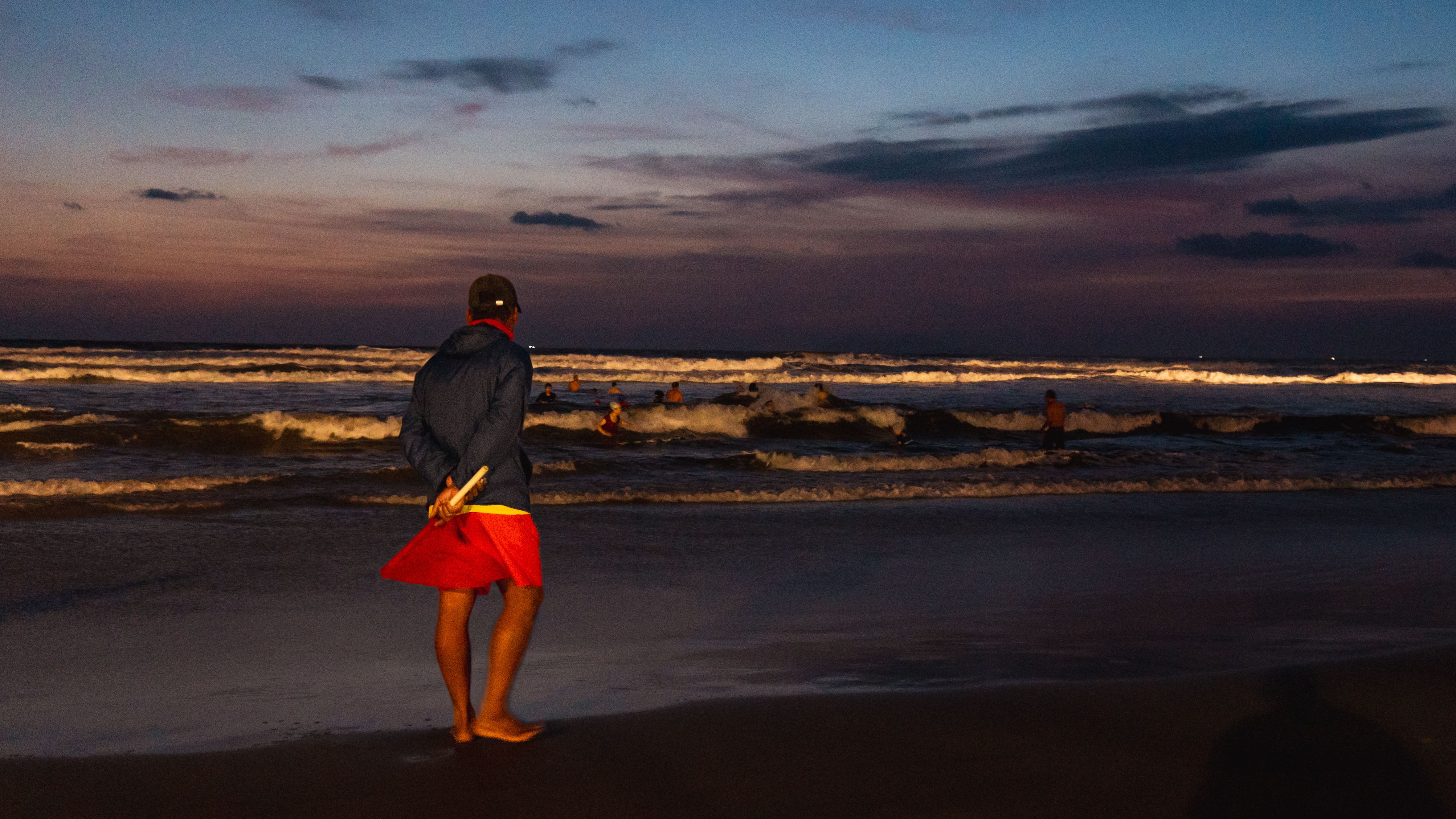 Gratis Livredder står på stranden og holder øje med svømmerne i skumringen. Lagerfoto
