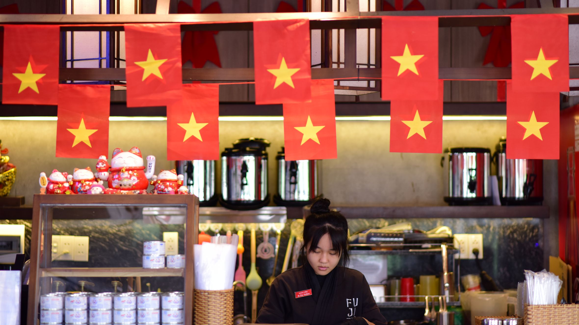Vibrant Vietnamese restaurant interior featuring national flags and attentive staff member at the counter.