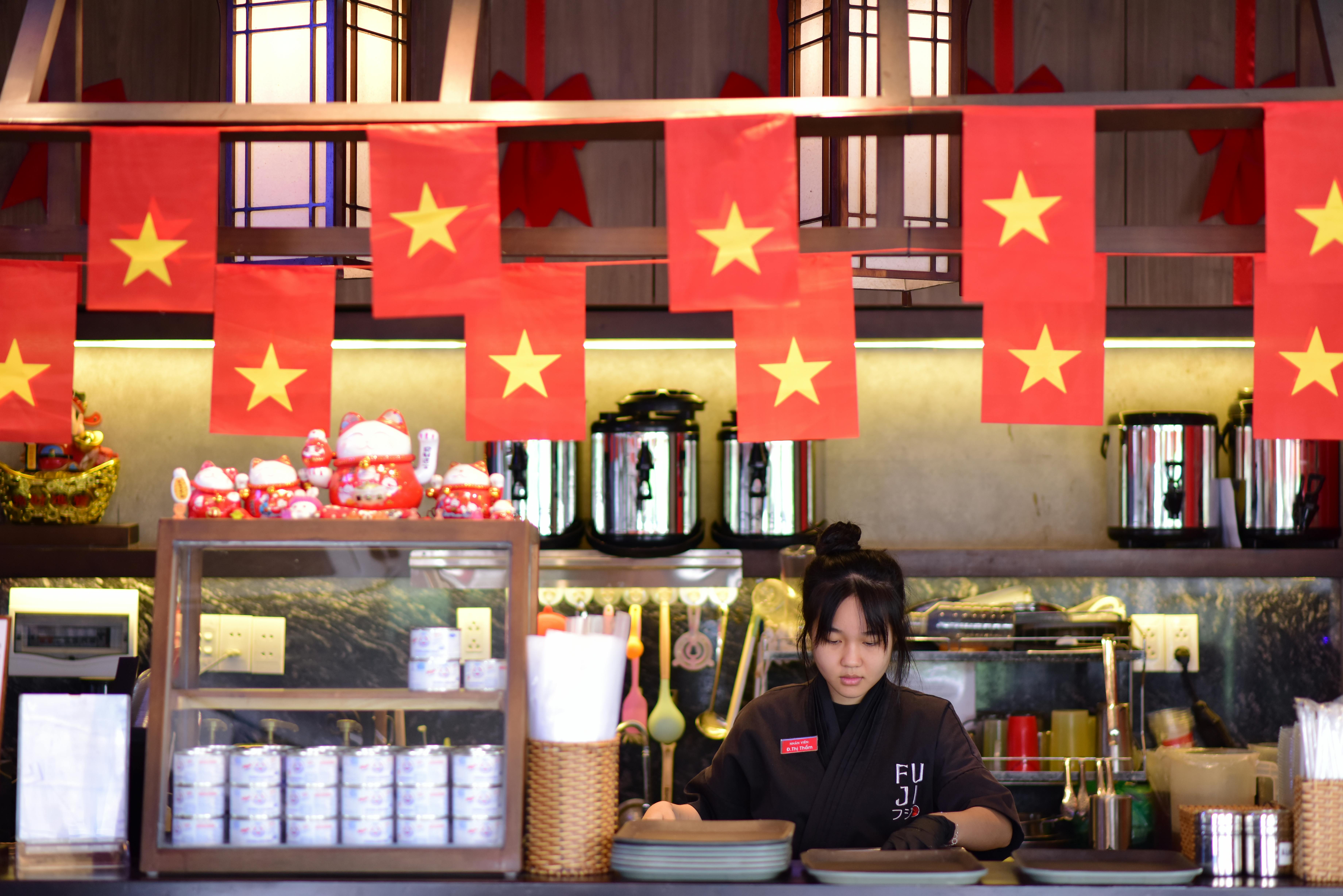 Cozy Vietnamese-themed restaurant interior featuring staff member and cultural decor.