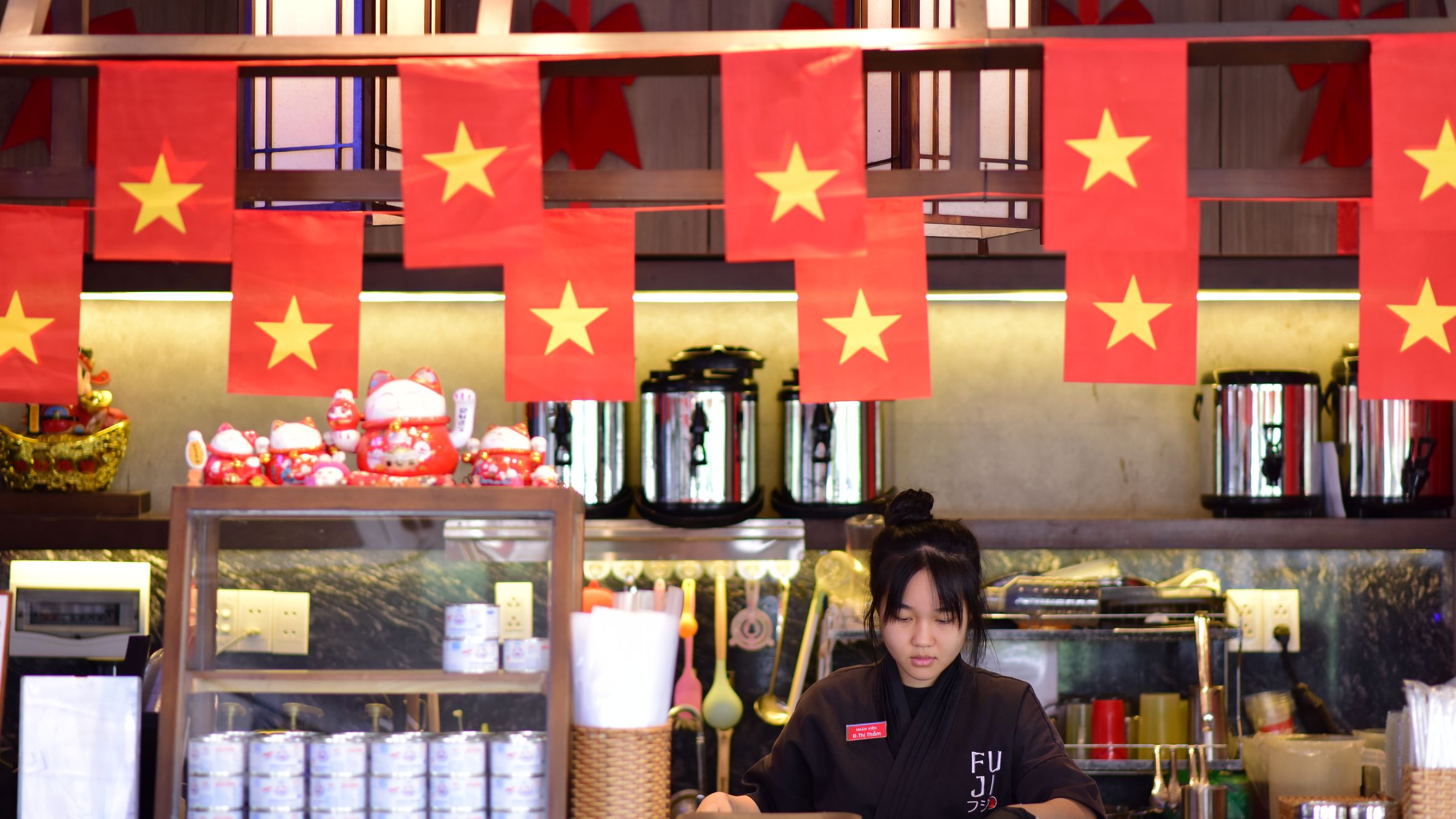 Cozy Vietnamese-themed restaurant interior featuring staff member and cultural decor.