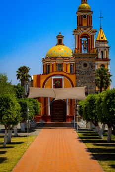 Vibrant church with baroque architecture, Cholula, Puebla, Mexico, under a clear blue sky.