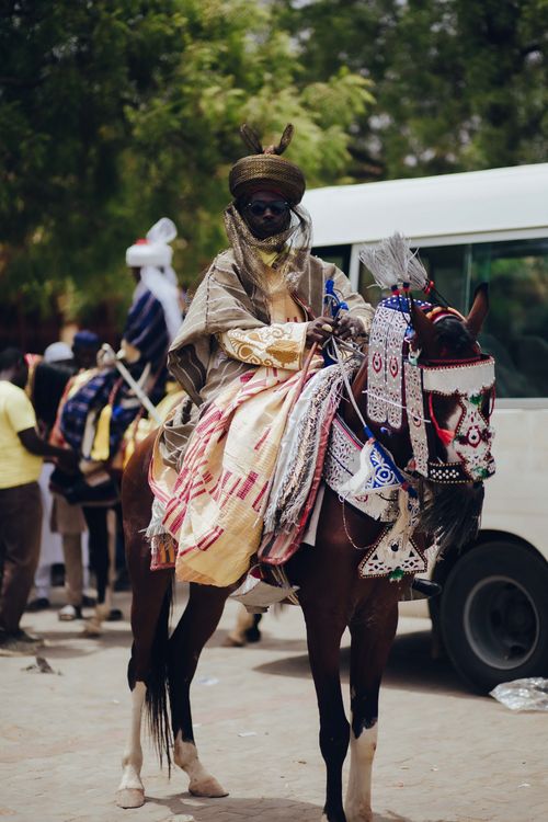 Free A Nigerian man in traditional attire sits on a decorated horse, showcasing vibrant cultural heritage. Stock Photo