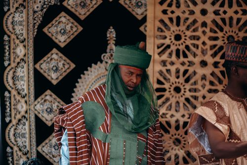 Free Nigerian men in traditional attire with intricate cultural patterns in the background. Stock Photo